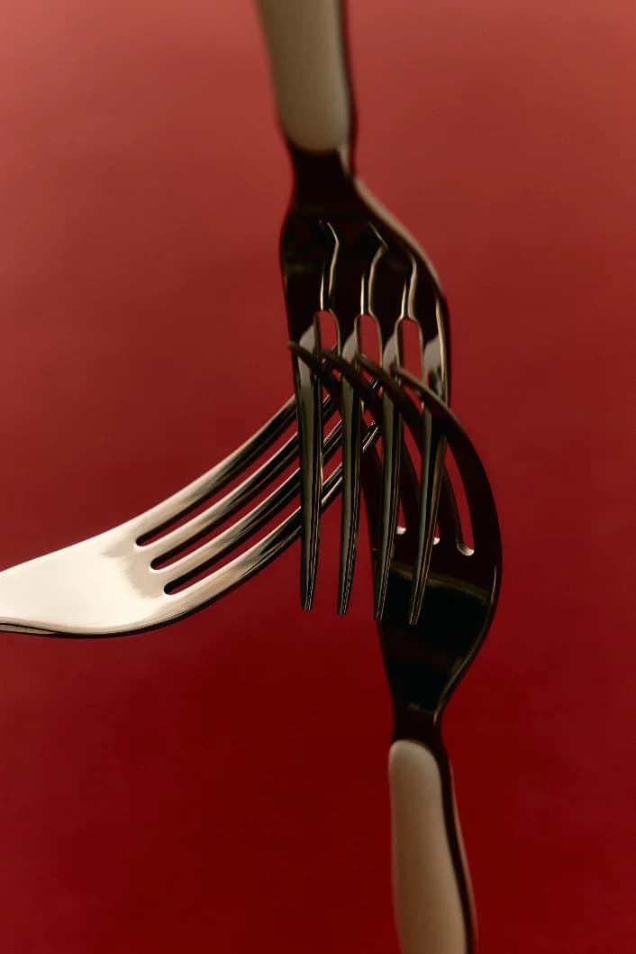 Two forks interlocked against a deep red backdrop