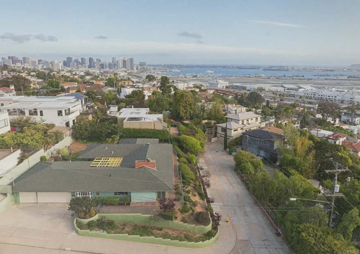 Aerial view of Casa Walnut, a low 1950s ranch house on a hillside with the city and bay beyond